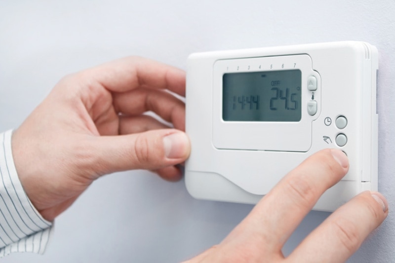 Close up of a man adjusting a thermostat, Different Types of Thermostats | Comfortable Design Inc. | Lancaster, PA