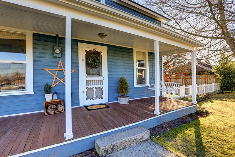 Front of blue house with a wooden deck, How to Save Money on Your Air Conditioning & Energy Bill in the Summer
